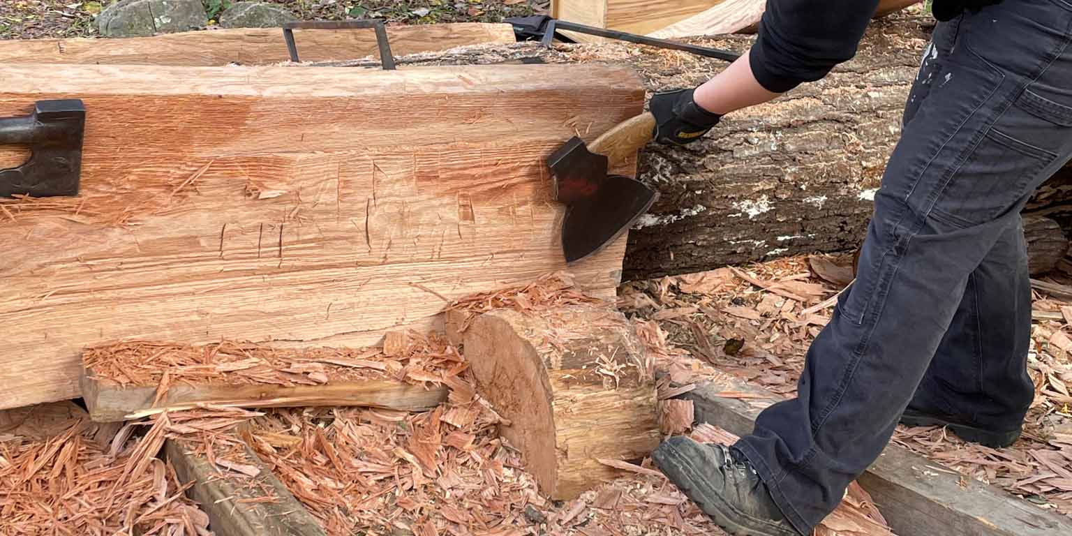 red oak log being cleaned up with an axe